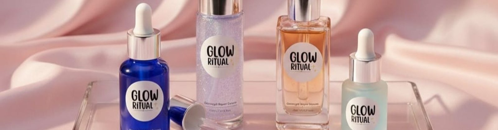 Luxury skincare product photography of a premium night serum bottle labeled “Glow Ritual – Overnight Repair Serum”, deep midnight blue glass bottle with silver dropper, placed on black marble surface, soft moonlight glow from window, silky satin fabric in background, subtle stars reflection, high-end beauty campaign style, cinematic lighting, ultra realistic, 8k resolution, shallow depth of field, premium aesthetic, elegant shadows, glowing skin concept add the 3-4 types of night serum in it with different colour add this logo on the all of the products